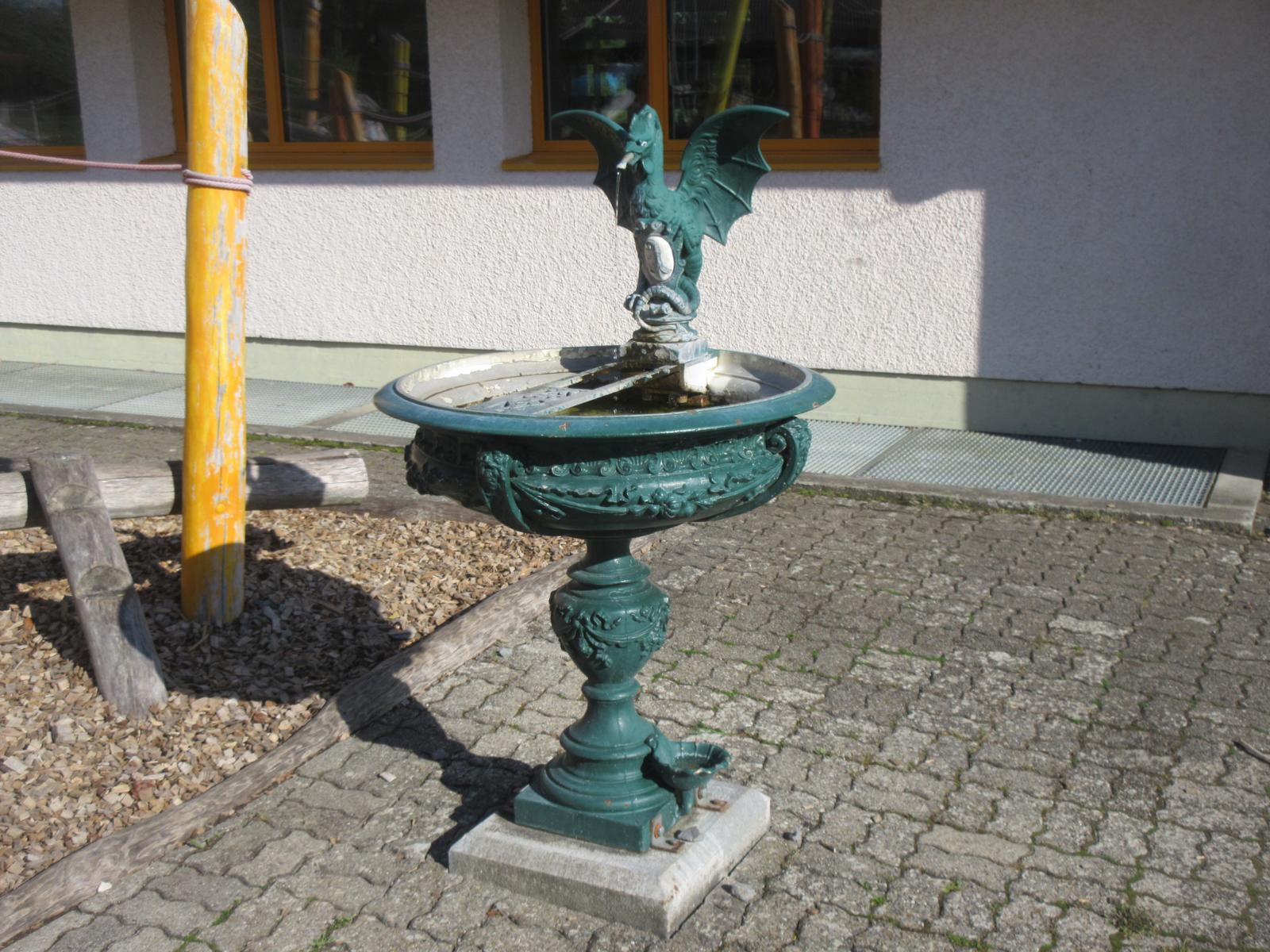 Schulhaus - Basiliskenbrunnen * *** 2002 *** Gusseisen, Grün gestrichen *** Bronze (Basilisk) *** Geschenk der Stadt Basel *