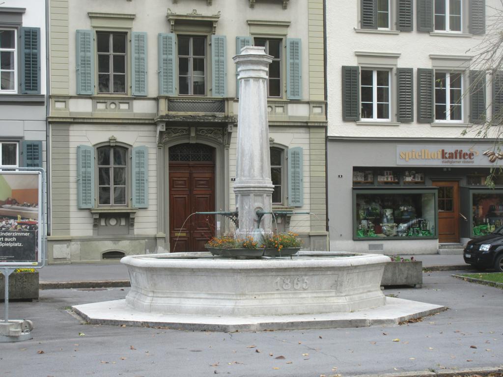 Spielhof *** 1865 *** Solothurner Kalk mit Spiralschnecken (Nerineen) *** Solothurnerkalk; 4 bronzene Wasserspeier *** oktogonaler, aus zwei monolithischen Stücken von ca. 4 x 2 m zusammengefügter Brunnentrog
