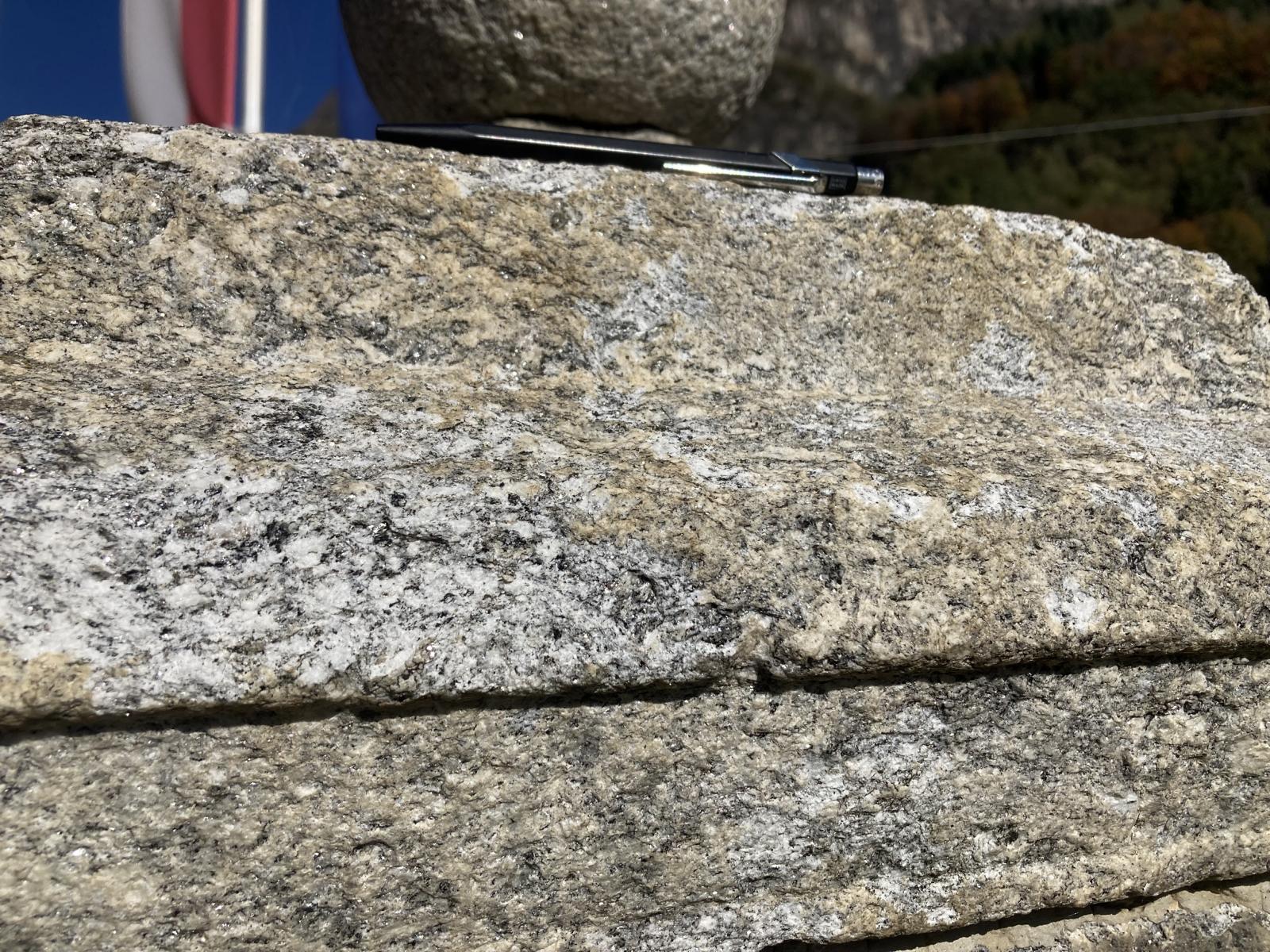 Detail des Stockes, Deckplatte unterhalb der Kugel, Leventina-Gneis - ein Granitgneis mit Biotit (schwarzer Glimmer) und Muskovit (heller, z.T. silbrig glänzender Glimmer). Im frischen Bruch sind auch der weisse Feldspat und der durchsichtige Quarz zu erkennen. Die Verwitterungsfarbe ist bräunlich. Detail des Stockes, Deckplatte unterhalb der Kugel, Leventina-Gneis - ein Granitgneis mit Biotit (schwarzer Glimmer) und Muskovit (heller, z.T. silbrig glänzender Glimmer). Im frischen Bruch sind auch der weisse Feldspat und der durchsichtige Quarz zu erkennen. Die Verwitterungsfarbe ist bräunlich.