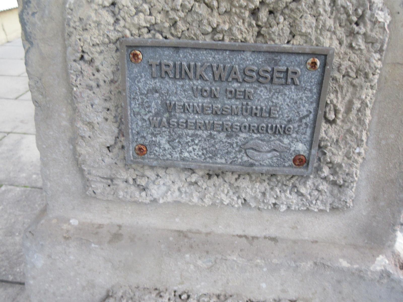 Betonstock mit Zierflächen aus rauem grobem Beton; darauf Infotafel der Wasserversorgung. Betonstock mit Zierflächen aus rauem grobem Beton; darauf Infotafel der Wasserversorgung.
