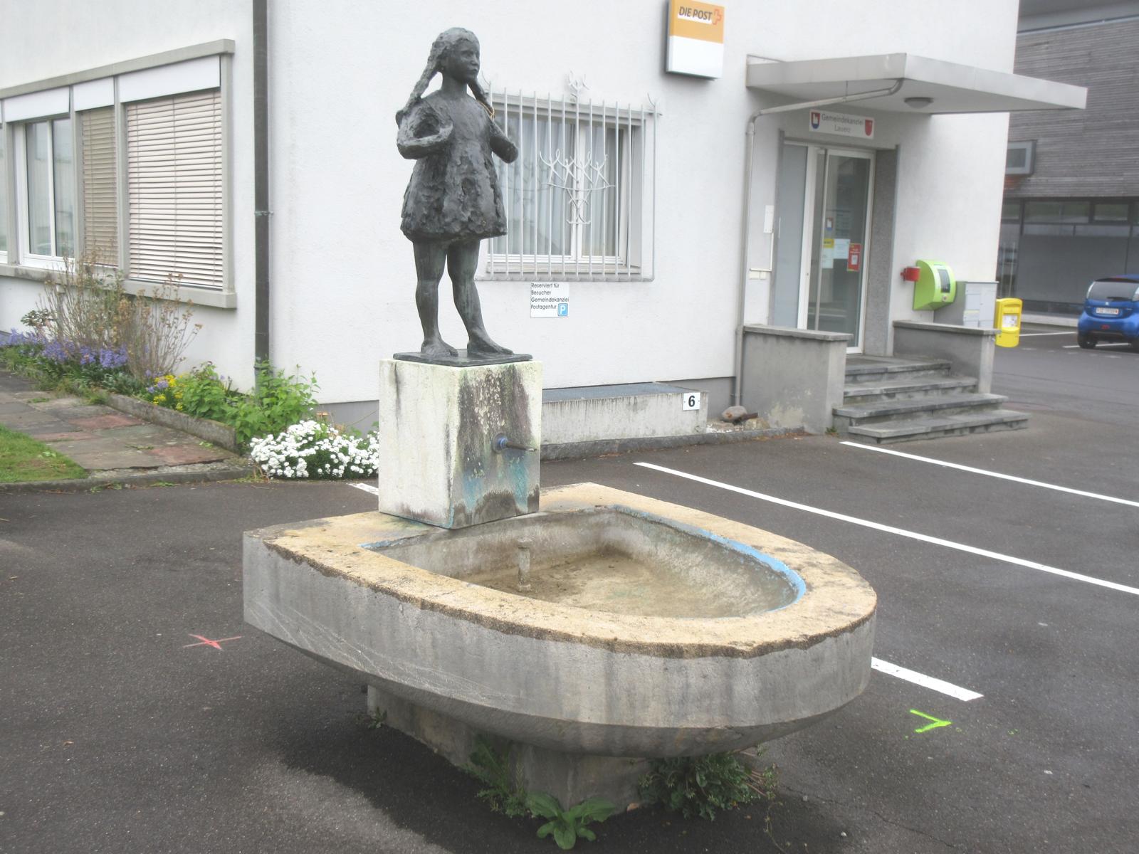 Husmatt: Schulhausbrunnen (Schulmädchen) *** 1963 *** gelblicher Kalk, viele Muscheln, u.a. Nerineen (Spiralschnecken) *** Bronze *** Bildhauer: <a href="http://www.rolfbrem.ch" target="_blank">Rolf Brem (1926-2014)</a>